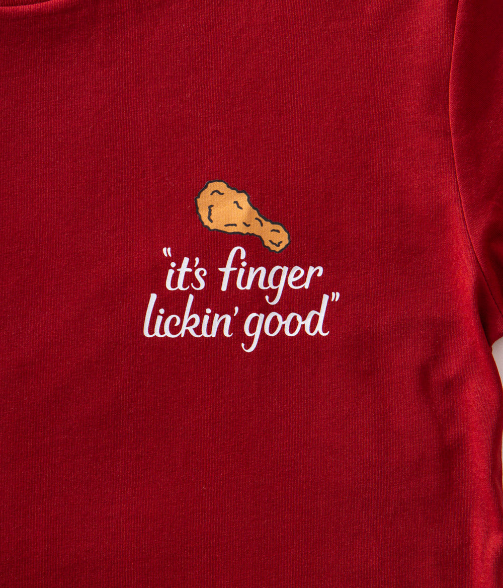 close up view of KFC red tee shirt with chicken drumstick and 'it's finger lickin' good' branding