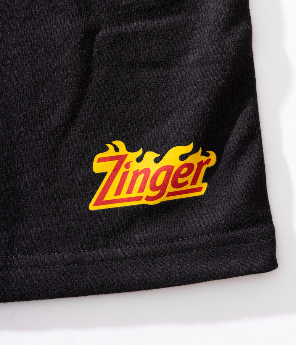 zoomed in view of KFC black shorts with 'Zinger' logo