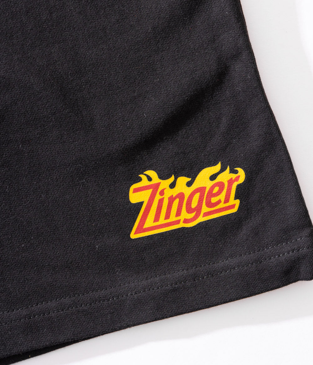 zoomed in view of KFC black shorts with 'Zinger' logo